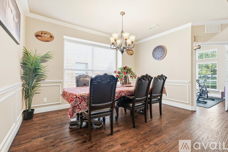 A dining room with a table set for four and a chandelier.