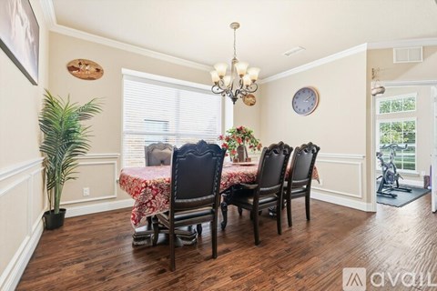 A dining room with a table set for four and a chandelier.