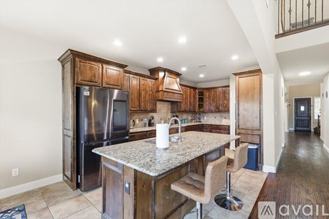 A kitchen with a granite countertop and wooden cabinets.