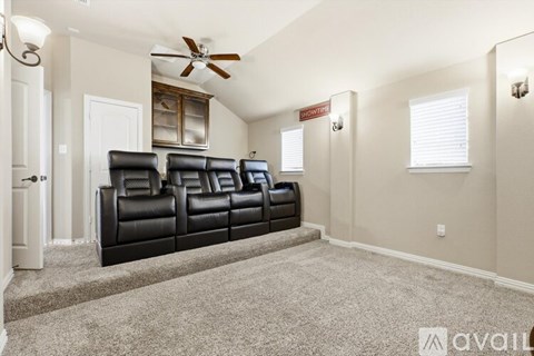 A living room with a row of black leather chairs and a ceiling fan.