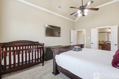 A bedroom with a bed, dresser, and a ceiling fan.