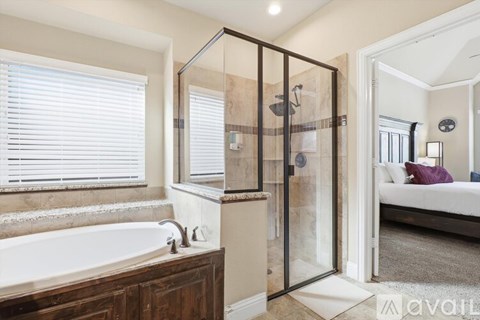 A bathroom with a glass shower enclosure and a bathtub.