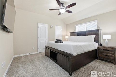 A bedroom with a large bed, a ceiling fan, and a carpeted floor.