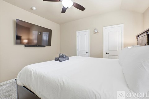 A bedroom with a bed, a ceiling fan, and a mirror on the wall.