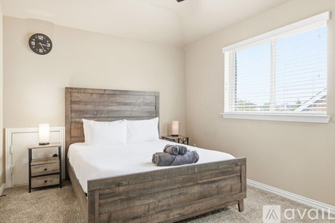 A bedroom with a bed, nightstands, and a clock on the wall.