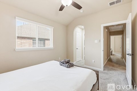A bedroom with a bed, a ceiling fan, and a window with blinds.