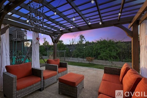 A patio with a wicker sofa and ottoman under a pergola.