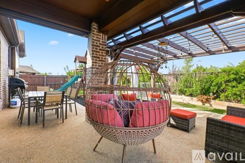 A patio with a wicker hanging chair and a table.