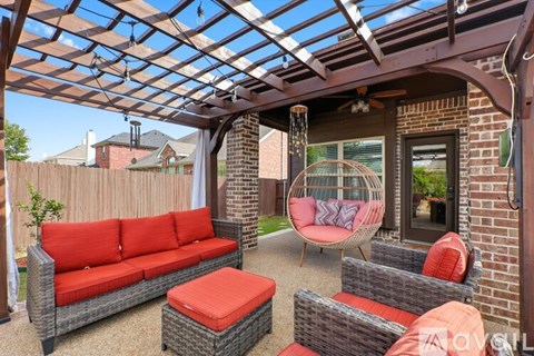 A patio with a red couch and a hanging chair.