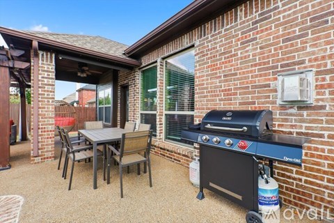 A patio with a table, chairs, and a grill.
