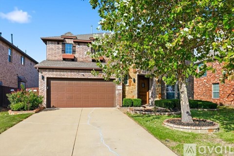 A house with a brown garage door and a tree in front.