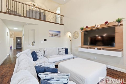 A living room with a white couch and a television on a wooden stand.