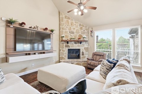A living room with a stone fireplace and a flat screen TV.