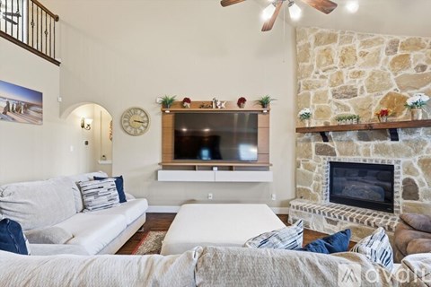 A living room with a stone fireplace and a flat screen TV mounted above it.
