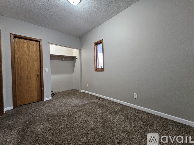 A room with a brown door and a window with a white frame.