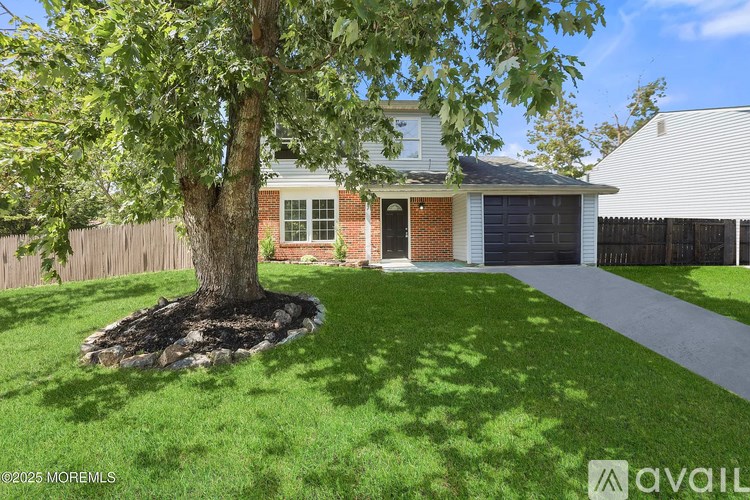 A tree in a grassy area in front of a house.