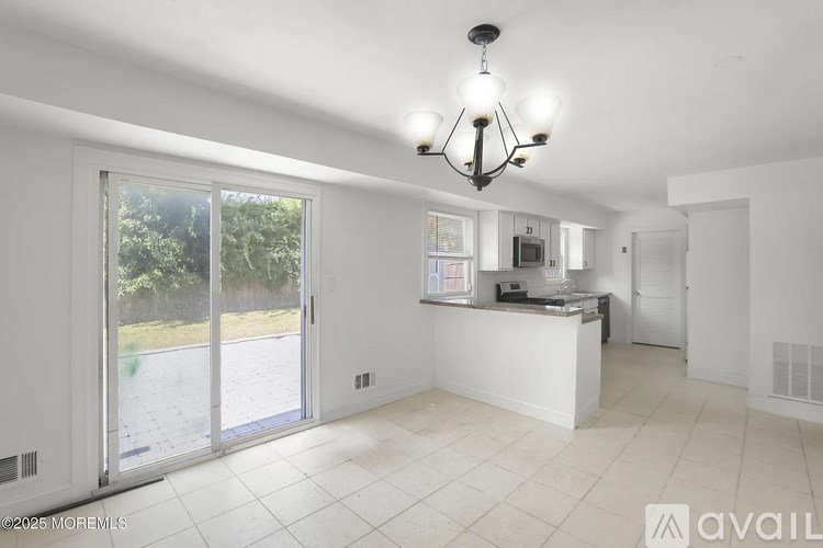 A large, empty room with a chandelier and a counter with a microwave.