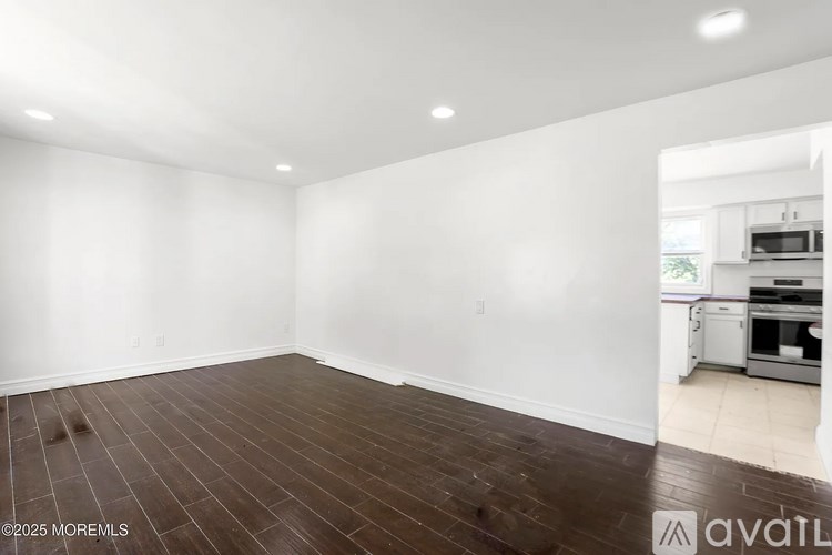 A large empty room with wooden flooring and white walls.