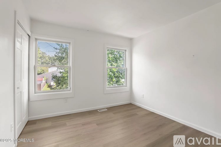 A room with two windows and wooden flooring.