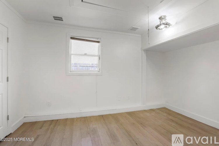 A room with a window and wooden flooring.