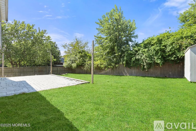 A backyard with a white fence and a green lawn.