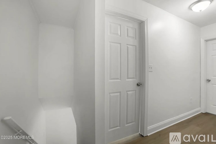 A white door is in the middle of a white room.