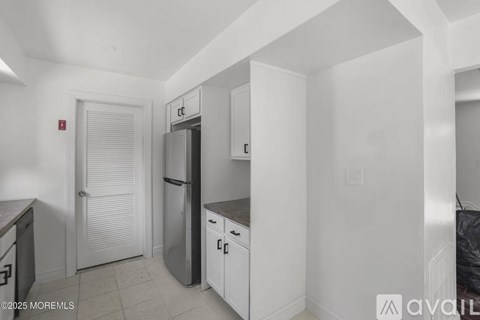 A kitchen with white cabinets and a black fridge.