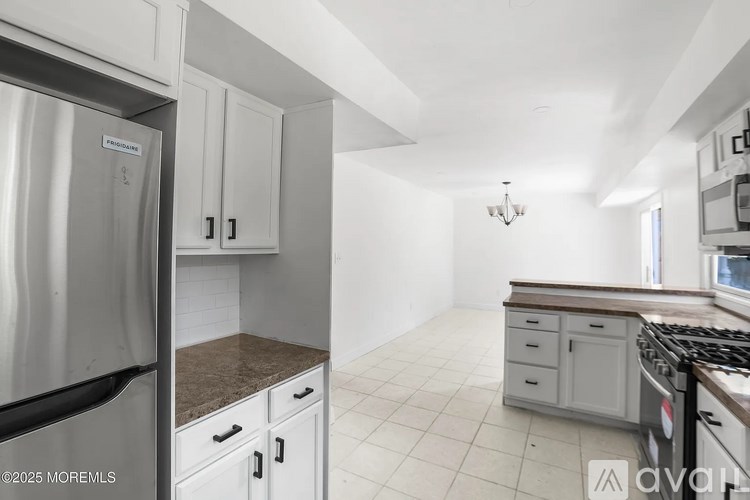 A kitchen with white cabinets and a stainless steel refrigerator.