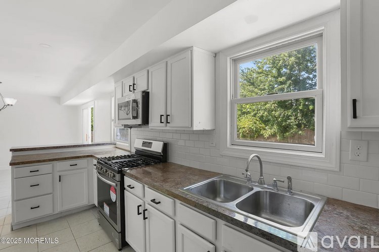 A kitchen with a stove, sink, and cabinets.