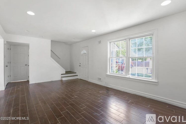 A room with wooden flooring and a large window.