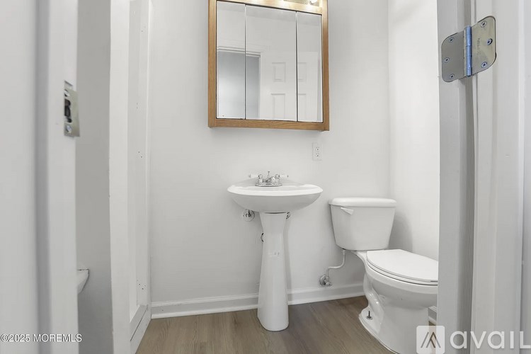 A bathroom with a sink, toilet, and mirror.