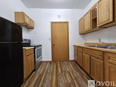 A kitchen with wooden cabinets and a black refrigerator.