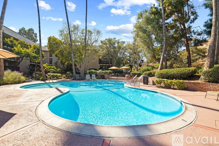 A large outdoor swimming pool surrounded by trees and bushes.
