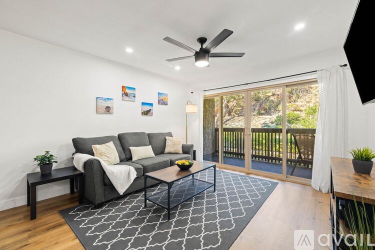 A living room with a grey couch, a black coffee table, and a ceiling fan.