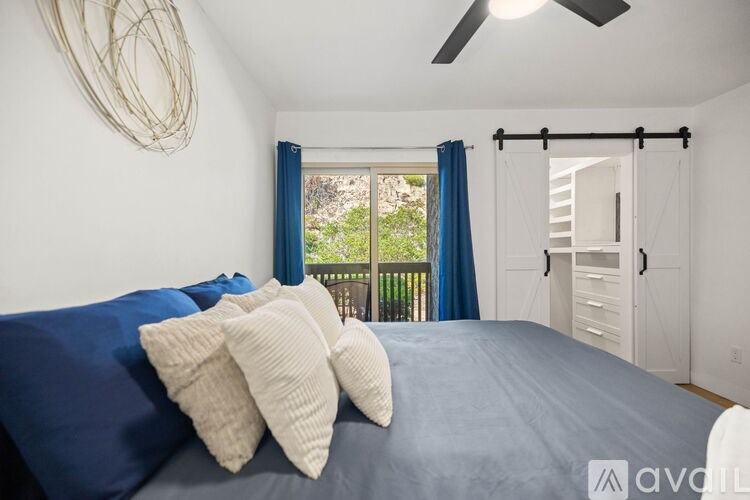 A bedroom with a bed, pillows, and a ceiling fan.