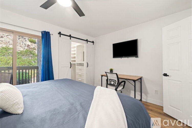 A bedroom with a bed, a chair, a table, and a television.