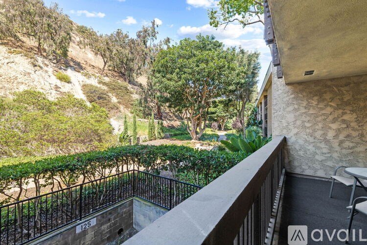 A balcony with a view of a hillside with trees and a house number 125.