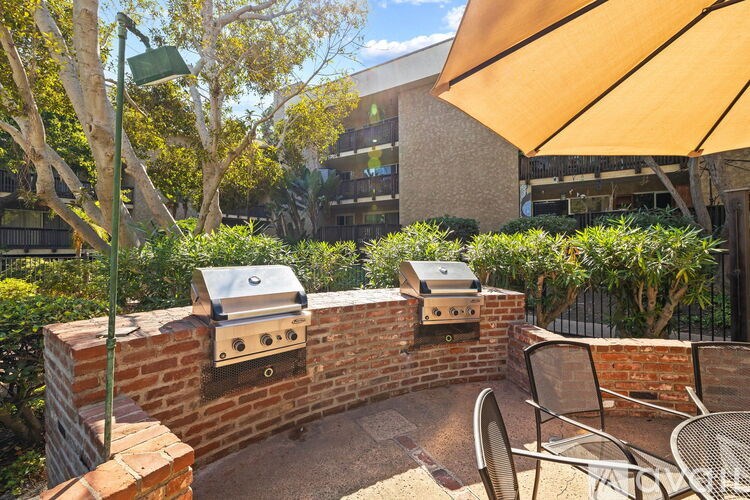 A patio with a brick wall and two grills.