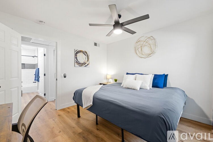 A bedroom with a bed, chair, and ceiling fan.
