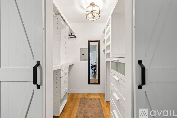 A hallway with white walls and a brown rug on the floor.