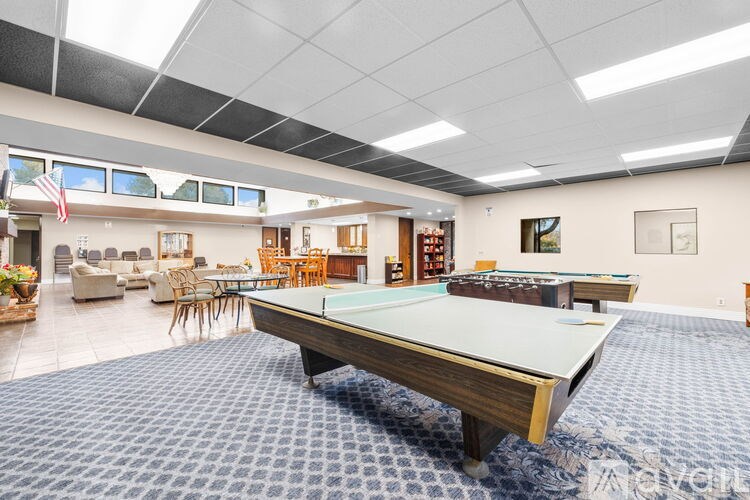 A pool table is in the middle of a room with a carpet and a sofa.