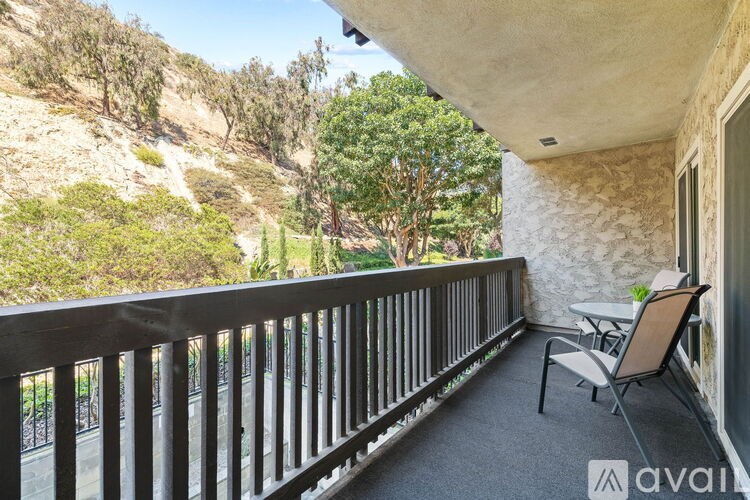 A balcony with a table and chairs overlooking a mountainous landscape.