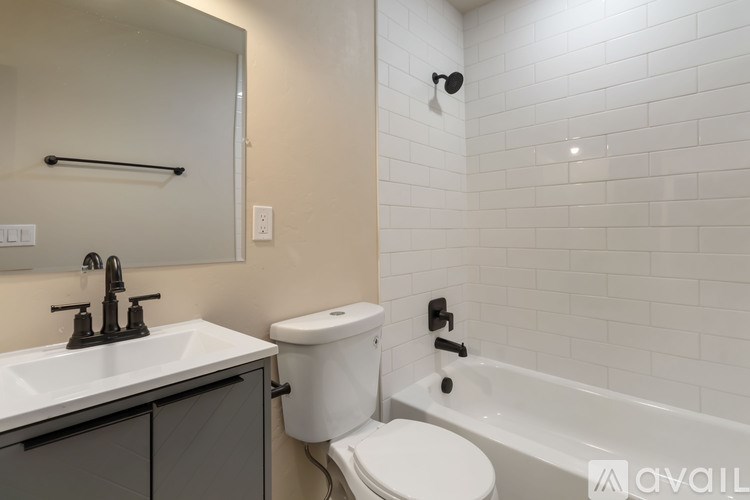 A white toilet is in a bathroom with a white sink and a white bathtub.