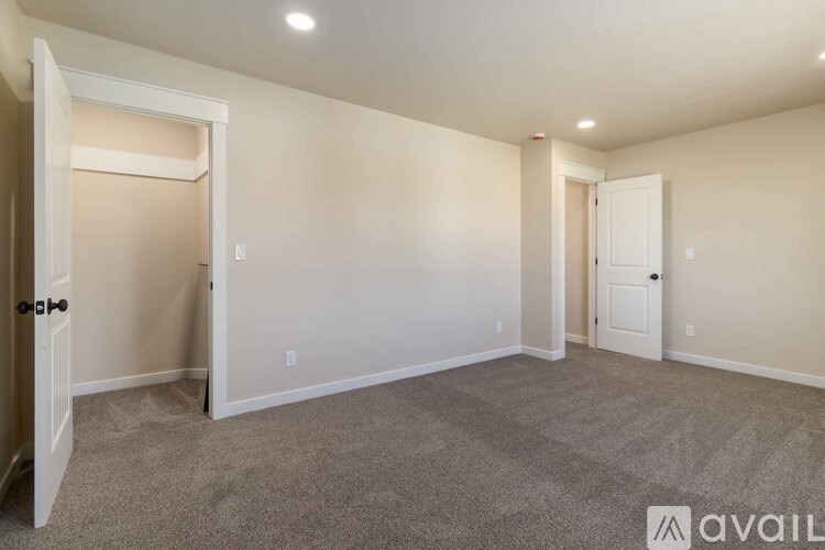 A room with carpeted floor and two doors, one of which is open.