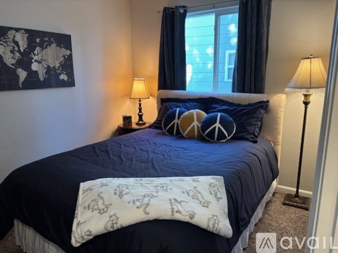 A bedroom with a bed, two lamps, and a world map on the wall.