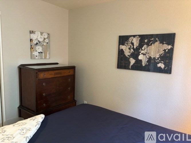 A bedroom with a world map on the wall and a wooden chest of drawers.
