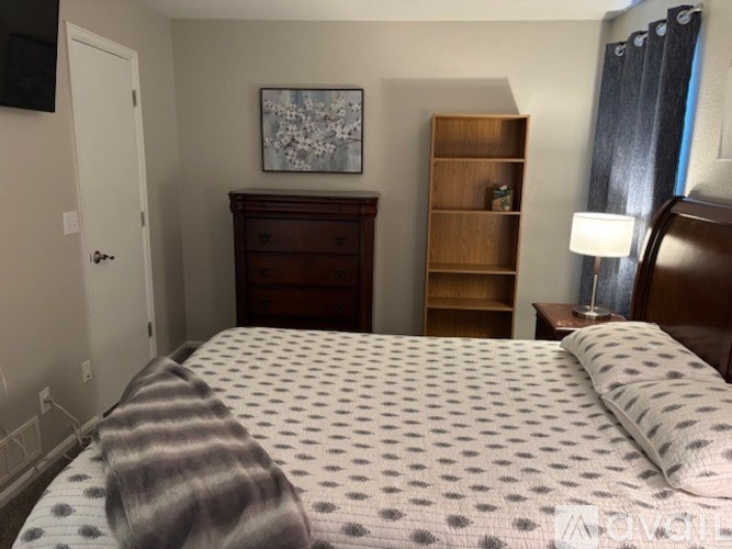 A bedroom with a bed, nightstand, and a painting on the wall.