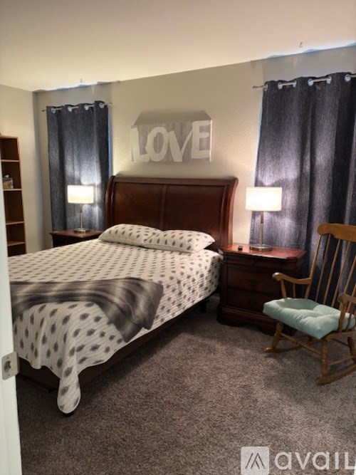 A bedroom with a bed, chair, and a wall decoration that says "LOVE".