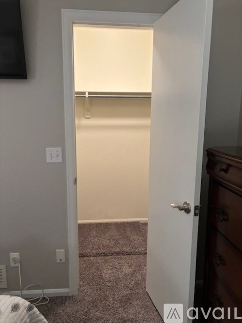 A white door is open to a room with a bed and a dresser.