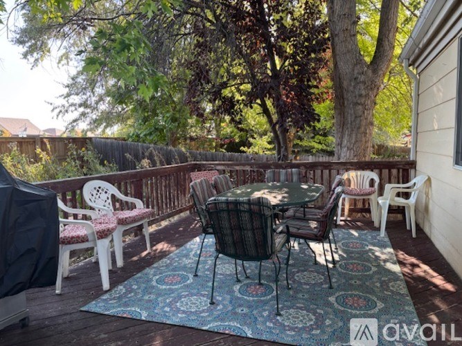 A patio with a table and chairs is surrounded by trees.